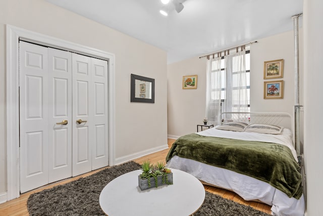 bedroom with light wood-style flooring, baseboards, and a closet