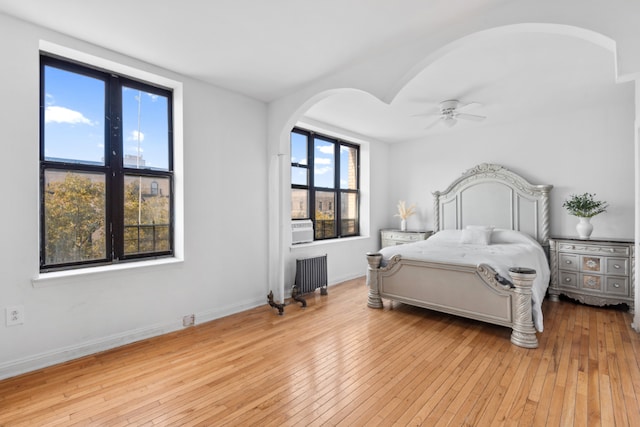 bedroom with ceiling fan, radiator heating unit, and light hardwood / wood-style flooring