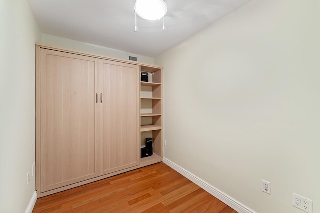 unfurnished bedroom featuring baseboards, a ceiling fan, visible vents, and light wood-style floors