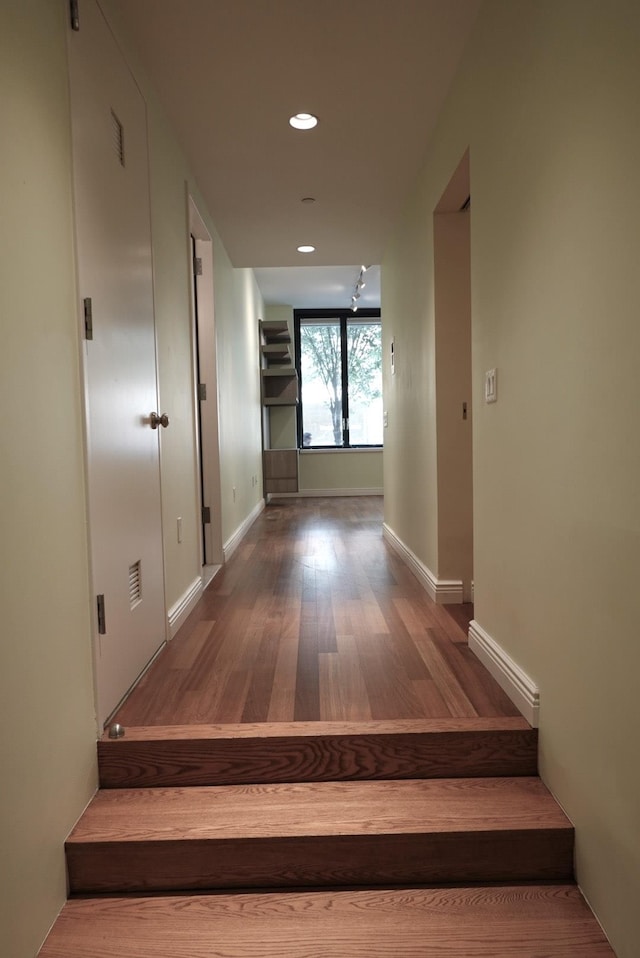 corridor with stairs, recessed lighting, wood finished floors, and baseboards