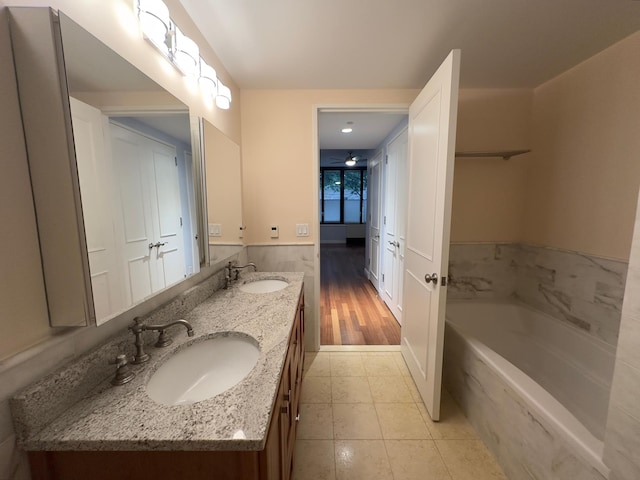 full bathroom with a garden tub, double vanity, tile patterned flooring, and a sink