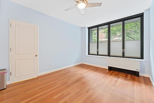 spare room with ceiling fan, radiator, and light hardwood / wood-style floors