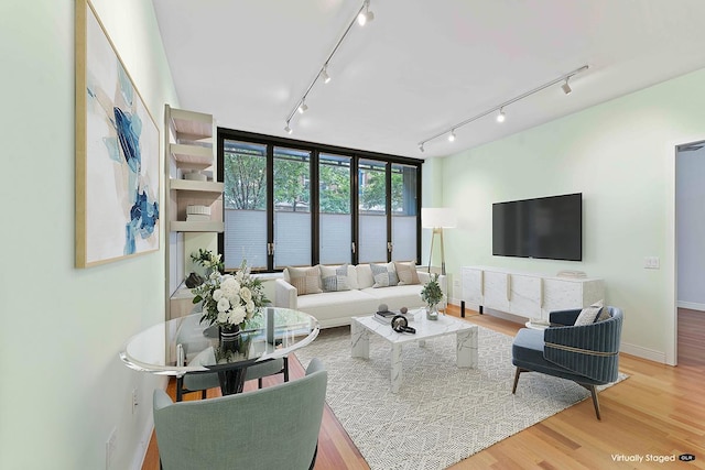 living area with rail lighting, baseboards, and wood finished floors