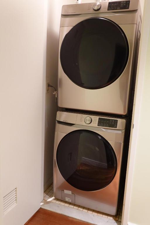 laundry room featuring stacked washer / dryer and wood-type flooring