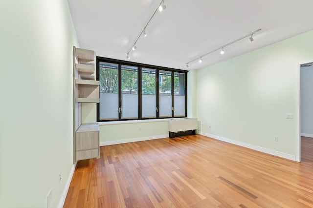 unfurnished room featuring light wood-type flooring, rail lighting, and baseboards