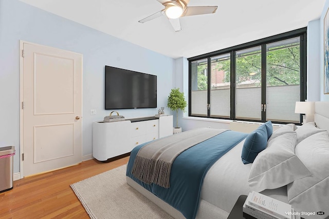 bedroom with light wood-type flooring, a ceiling fan, and baseboards