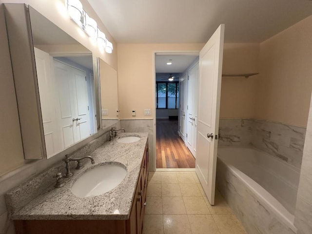 bathroom featuring tile patterned flooring, vanity, and a washtub