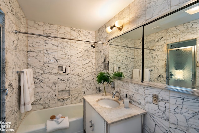 bathroom with vanity, tiled shower / bath combo, and tile walls