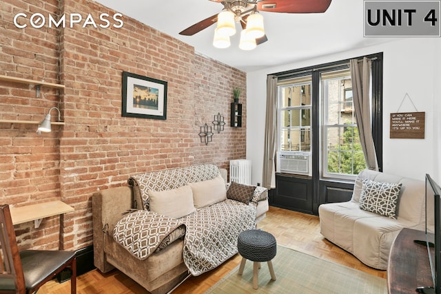 living room featuring cooling unit, brick wall, radiator heating unit, and ceiling fan