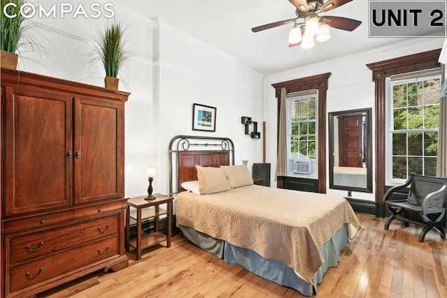 bedroom featuring ceiling fan, cooling unit, ornamental molding, and light wood-type flooring