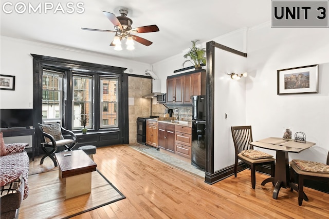 kitchen featuring ceiling fan, black appliances, crown molding, light hardwood / wood-style flooring, and dark brown cabinets