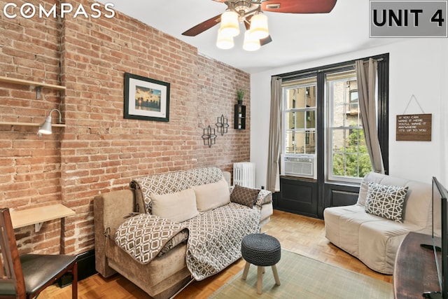 living room featuring light parquet flooring, brick wall, radiator heating unit, and cooling unit