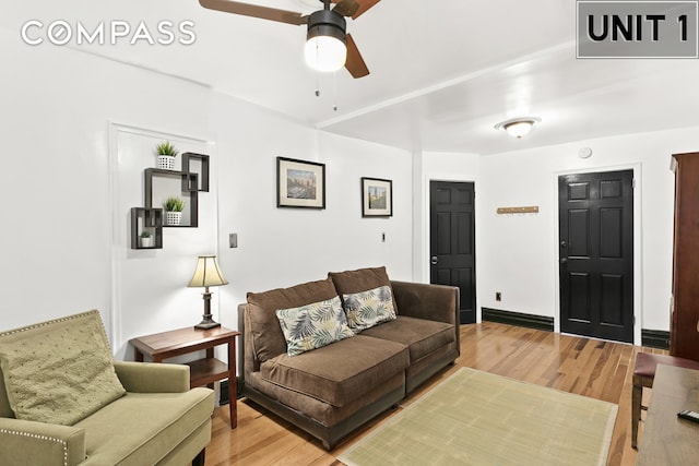 living room featuring baseboards, light wood-style floors, and a ceiling fan