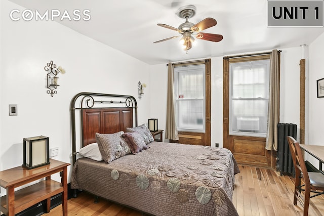 bedroom with light wood-style flooring, radiator, and ceiling fan