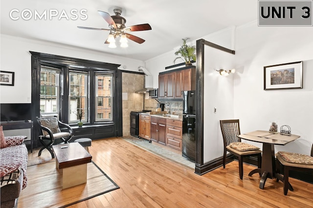 living room with a ceiling fan, light wood finished floors, and ornamental molding