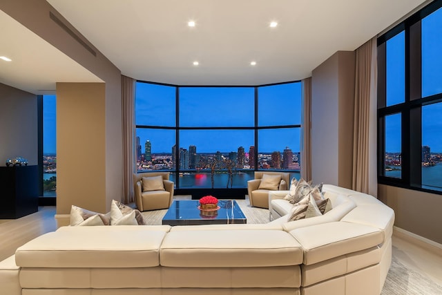 living room featuring recessed lighting, light wood-style floors, a city view, and floor to ceiling windows