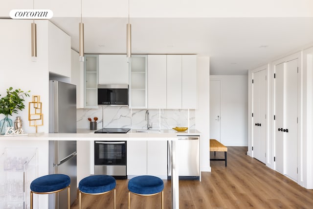 kitchen with white cabinets, backsplash, modern cabinets, and appliances with stainless steel finishes