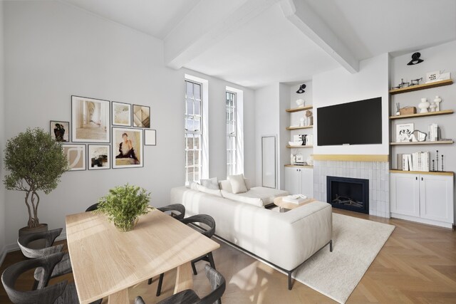 living room with light parquet floors, a tile fireplace, beam ceiling, and built in shelves