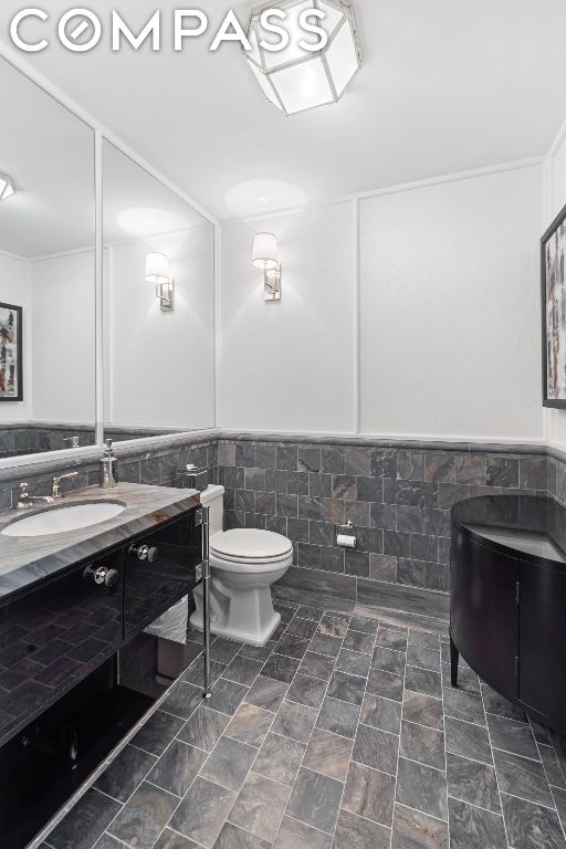 bathroom featuring vanity, toilet, and tile walls