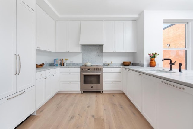 kitchen featuring light stone counters, white cabinetry, and high end stainless steel range