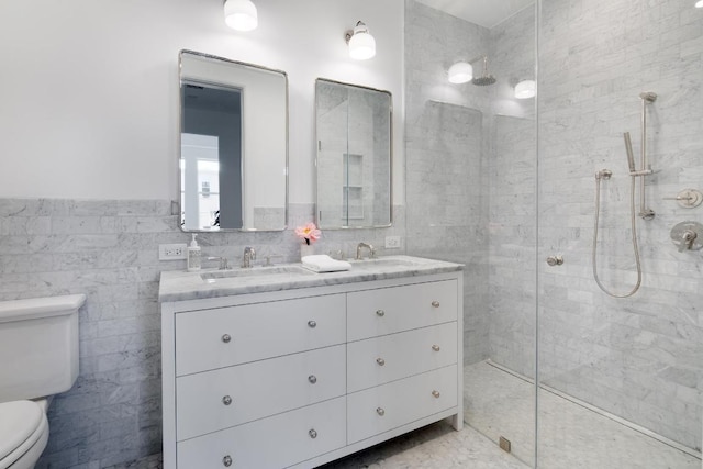 bathroom with tiled shower, vanity, toilet, and tile walls