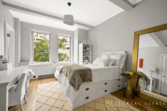 bedroom featuring light wood finished floors, beamed ceiling, and visible vents