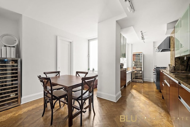 dining room featuring beverage cooler, rail lighting, and baseboards