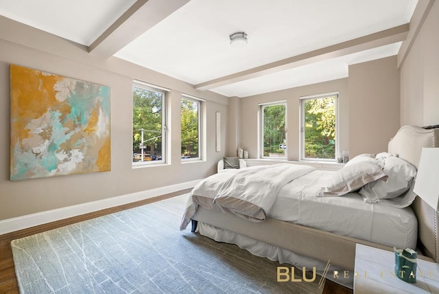 bedroom featuring beam ceiling, baseboards, and wood finished floors