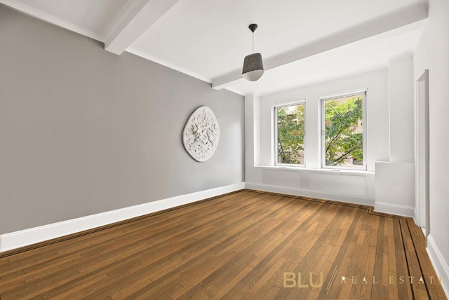 spare room featuring beamed ceiling, baseboards, and wood finished floors