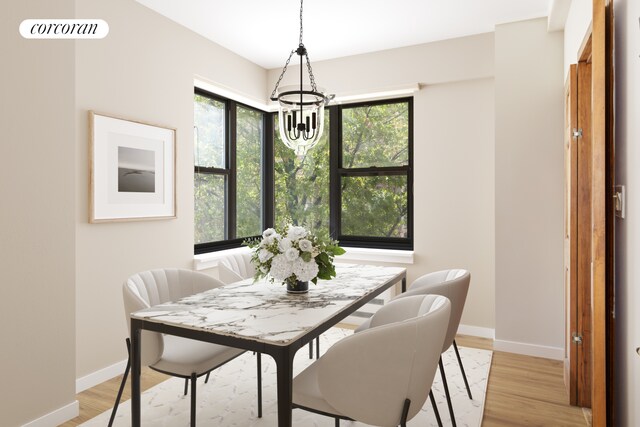 440 E 56th St Unit 6B, New York City, NY 10022 - dining area featuring a chandelier, baseboards, and light wood-style floors