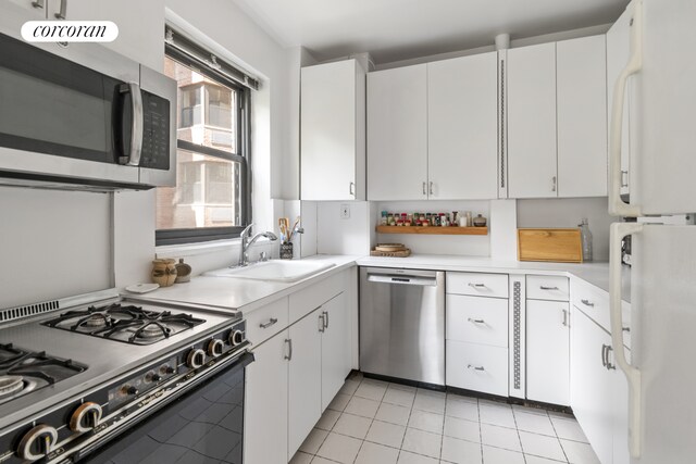 kitchen with white cabinets, stainless steel appliances, light countertops, and a sink