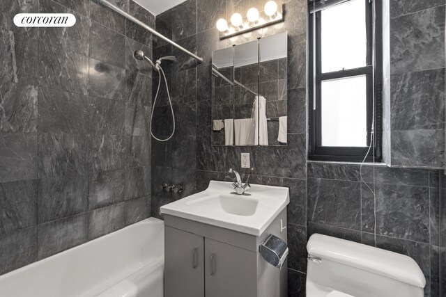 440 E 56th St Unit 6B, New York City, NY 10022 - full bathroom featuring tile walls, vanity, shower / bathtub combination with curtain, and toilet