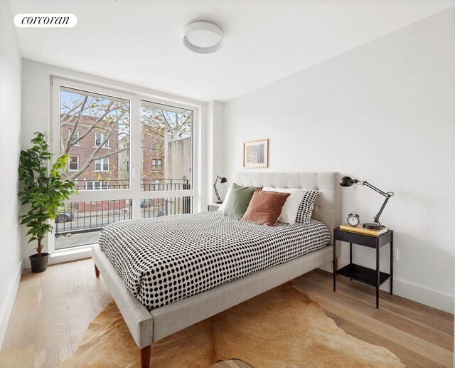 bedroom with wood finished floors, visible vents, and baseboards