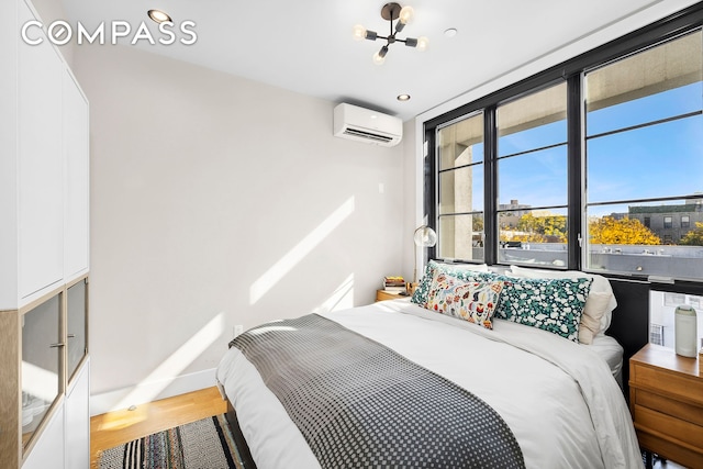 bedroom featuring an AC wall unit, wood finished floors, a chandelier, baseboards, and recessed lighting