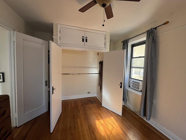 unfurnished bedroom with wood finished floors, cooling unit, a ceiling fan, and baseboards