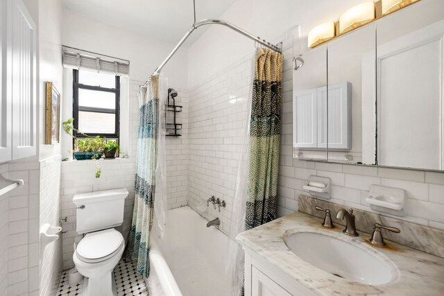 full bathroom with tile walls, toilet, shower / bath combo, vanity, and tile patterned floors