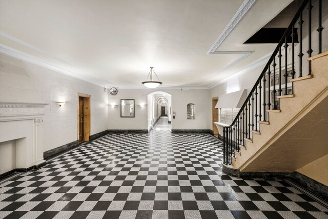 foyer entrance with arched walkways, baseboards, stairs, and ornamental molding