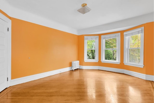 spare room featuring radiator heating unit, wood finished floors, plenty of natural light, and baseboards