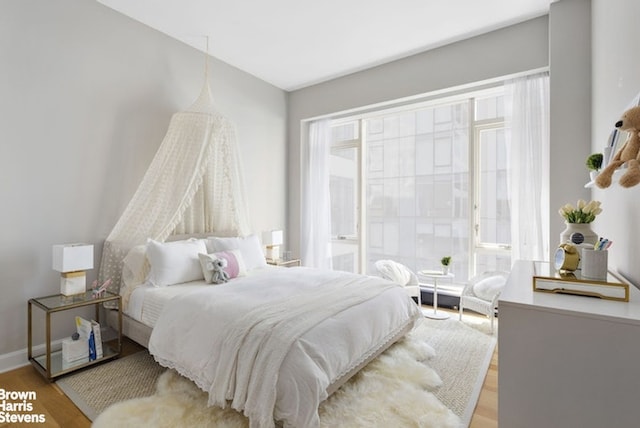 bedroom featuring baseboards, multiple windows, and wood finished floors