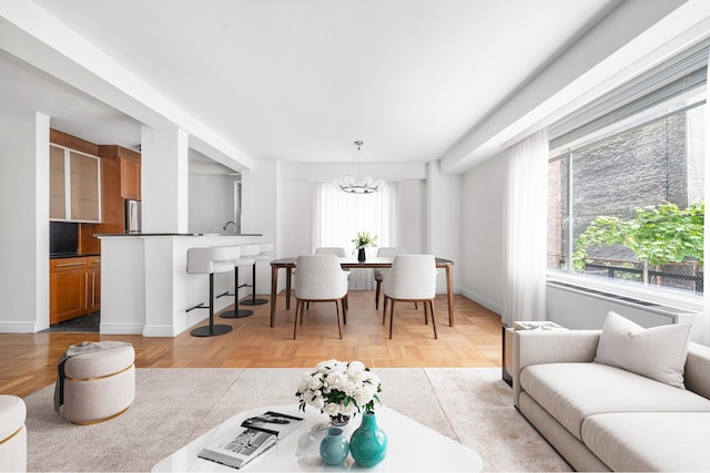 living area with a healthy amount of sunlight, an inviting chandelier, and baseboards