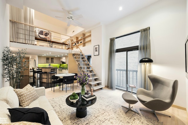 living area with recessed lighting, light wood-style flooring, ceiling fan, baseboards, and stairs