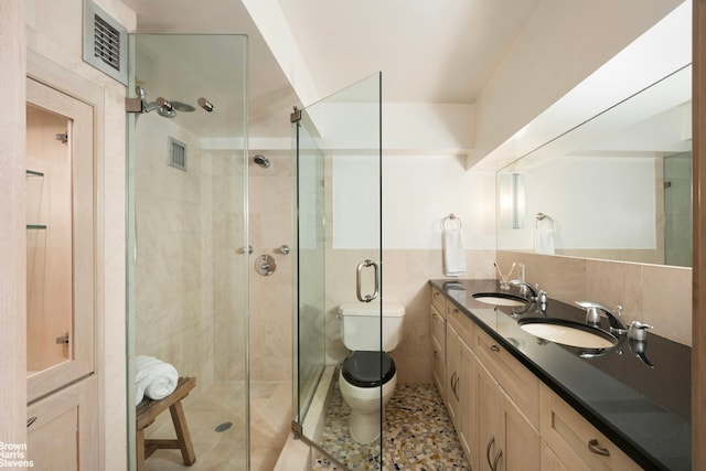 full bath featuring a stall shower, a sink, tile walls, and toilet