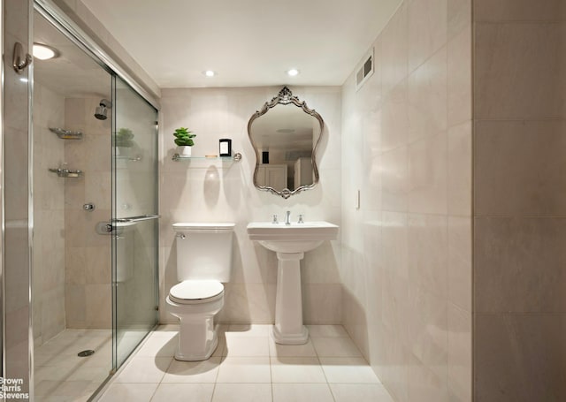 253 W 73rd St Unit 2G, New York City, NY 10023 - bathroom featuring tile walls, a stall shower, tile patterned flooring, and recessed lighting