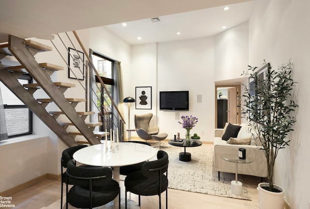 dining space with light wood finished floors, baseboards, stairway, a high ceiling, and recessed lighting