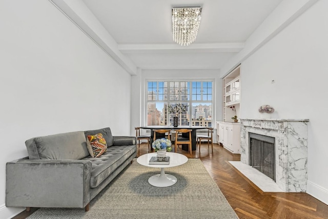 living room featuring dark parquet flooring, beamed ceiling, a premium fireplace, and a notable chandelier