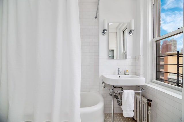 bathroom featuring tile patterned flooring, radiator, tile walls, and shower / bathtub combination with curtain