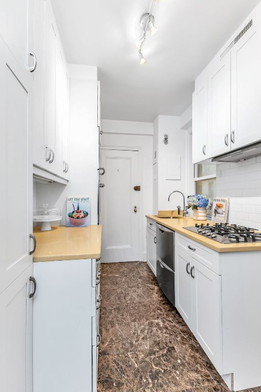 kitchen with decorative backsplash, appliances with stainless steel finishes, sink, and white cabinetry