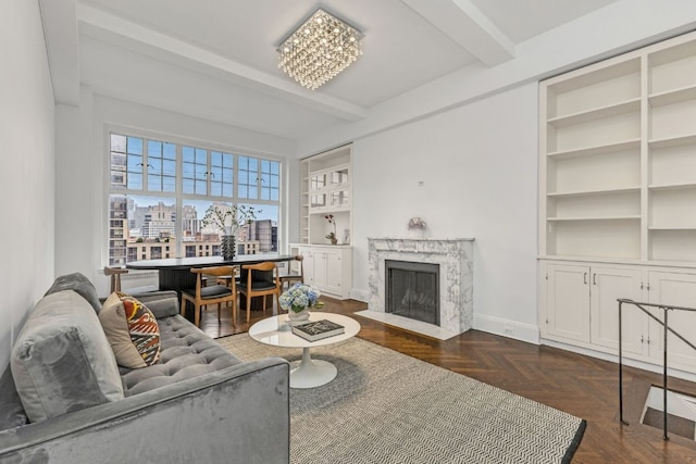 living room with a premium fireplace, built in features, a chandelier, dark parquet floors, and beam ceiling