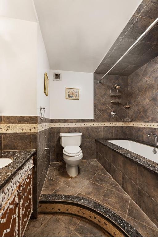 full bathroom featuring toilet, tile walls, plus walk in shower, and vanity