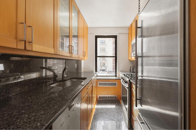 kitchen featuring stainless steel appliances, granite finish floor, a sink, and glass insert cabinets